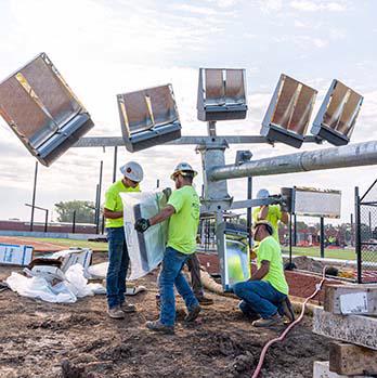 Putting together sports lights on the ground before standing up the poles.