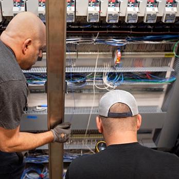 McElroy Electric technicians working in building automations control panel.