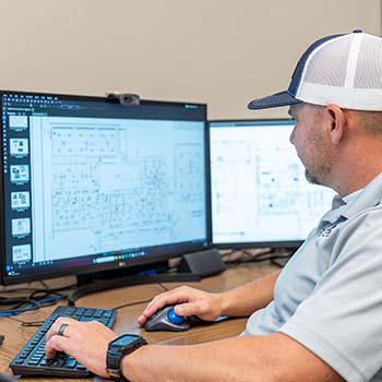 Project manager reviews electrical schematics on computer screen.