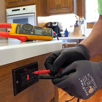 McElroy Electric electrician tests a kitchen outlet for faults.