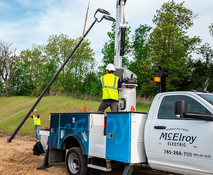 McElroy Electric crew positions a new light pole with our bucket-truck jib.